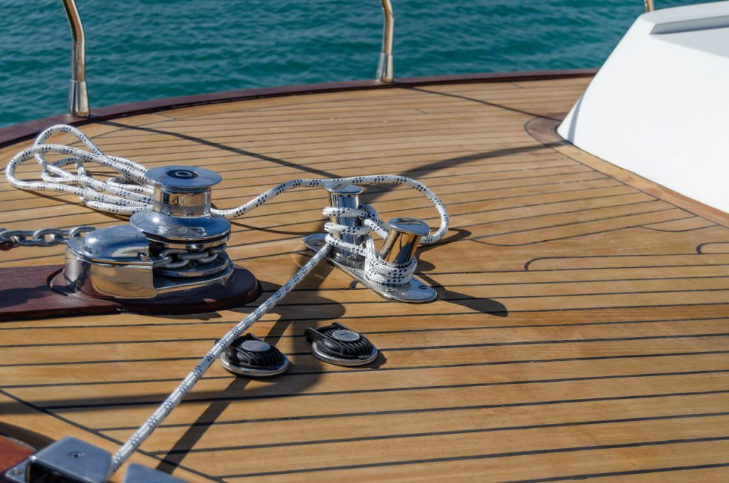 Stainless steel mooring equipment on the teak foredeck of the power boat.