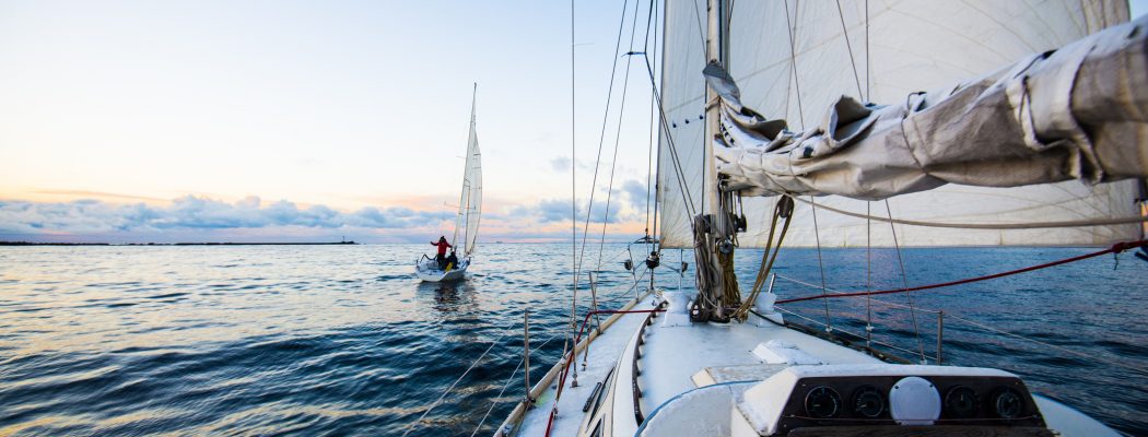 Clear evening sky at sunset. Two yachts sailing. A view from the deck to the bow and sails, close-up. Baltic sea, Latvia