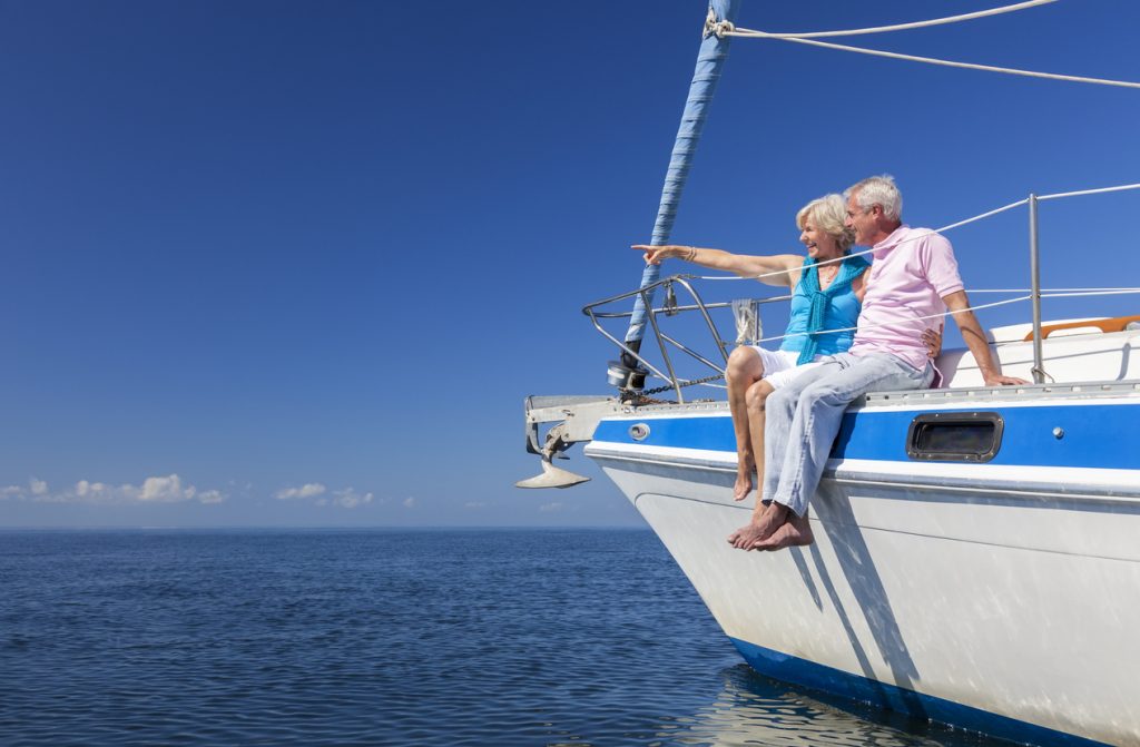 Senior couple sat on the side of a sail boat