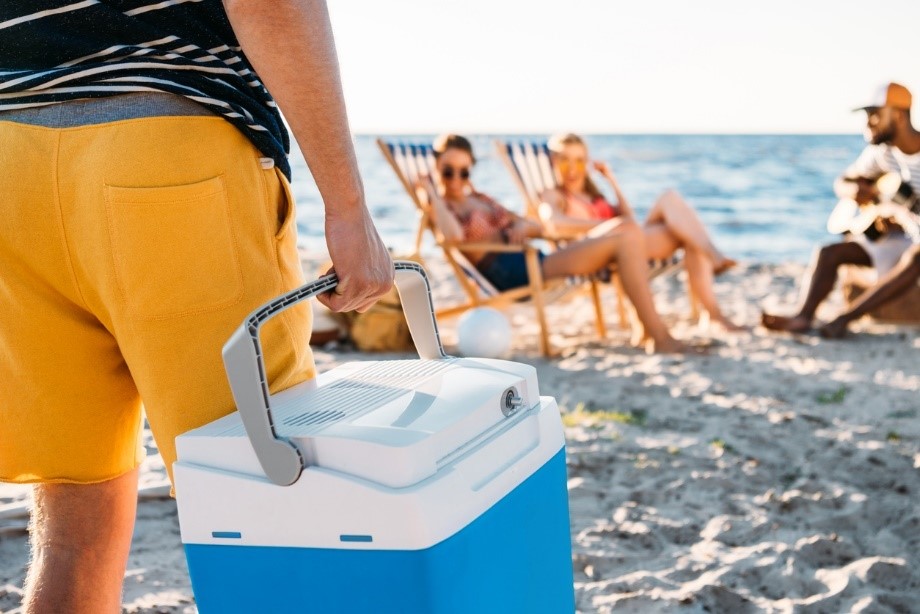 A person carrying a cooler on a beach
