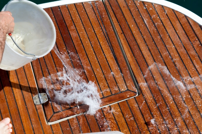 someone pouring water on a boat to clean it