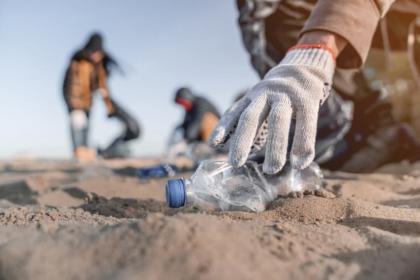 A person picking up a plastic bottle