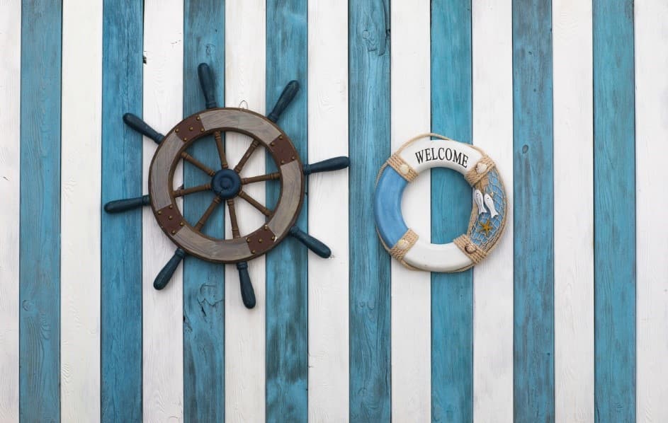 A steering wheel and life preserver on a blue and white striped wall