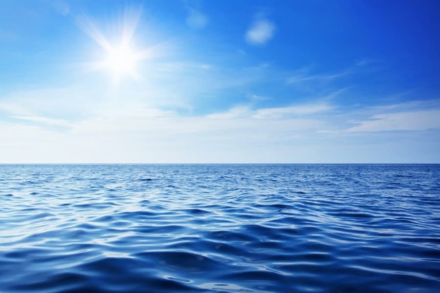 A blue sky and water with the sun